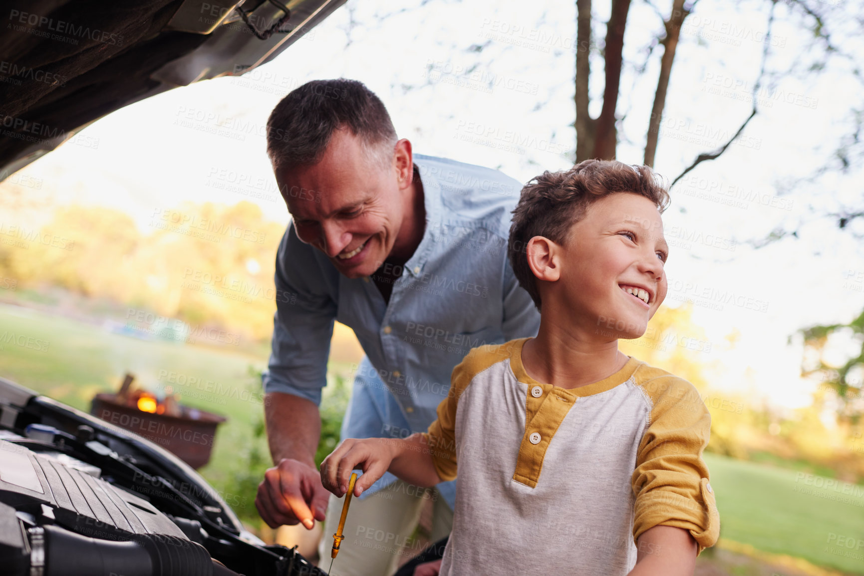 Buy stock photo Shot of a father showing his young son the engine of a car