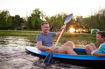 Buy stock photo Shot of a father and son rowing a boat together on a lake
