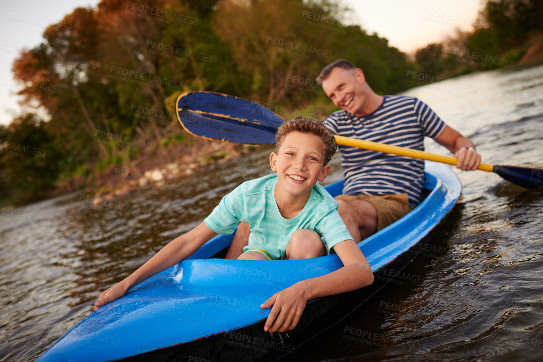 Buy stock photo Shot of a father and son rowing a boat together on a lake