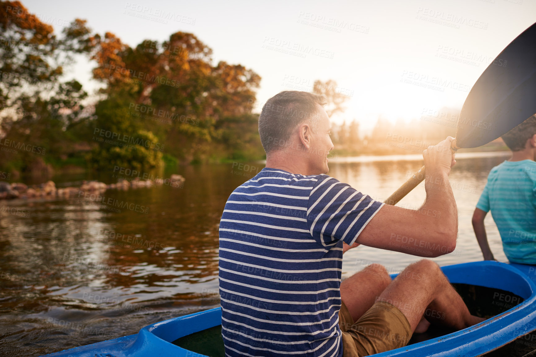 Buy stock photo Shot of a father and son rowing a boat together on a lake