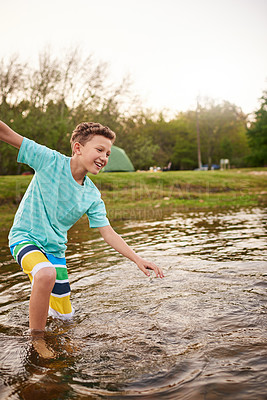 Buy stock photo Shot of a young boy splashing around in a lake
