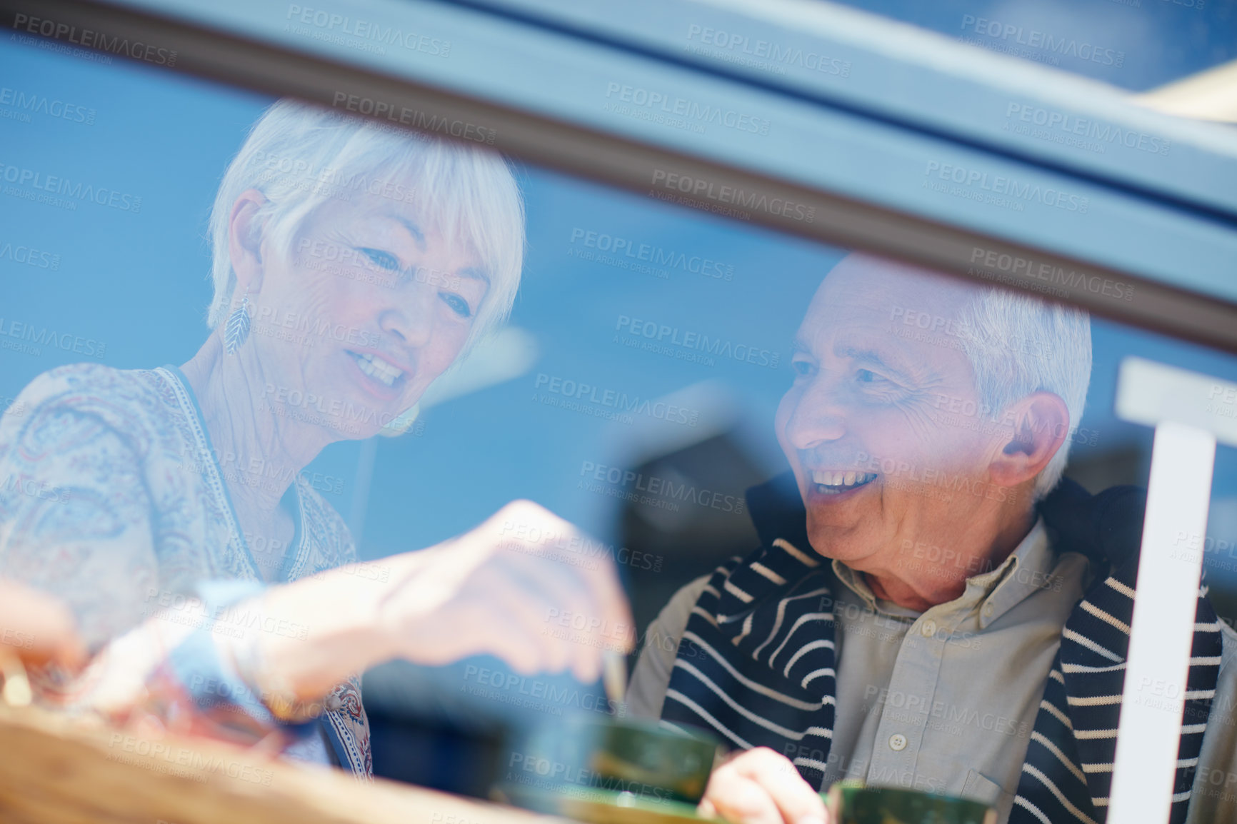 Buy stock photo Shot of a senior couple talking together at a cafe window