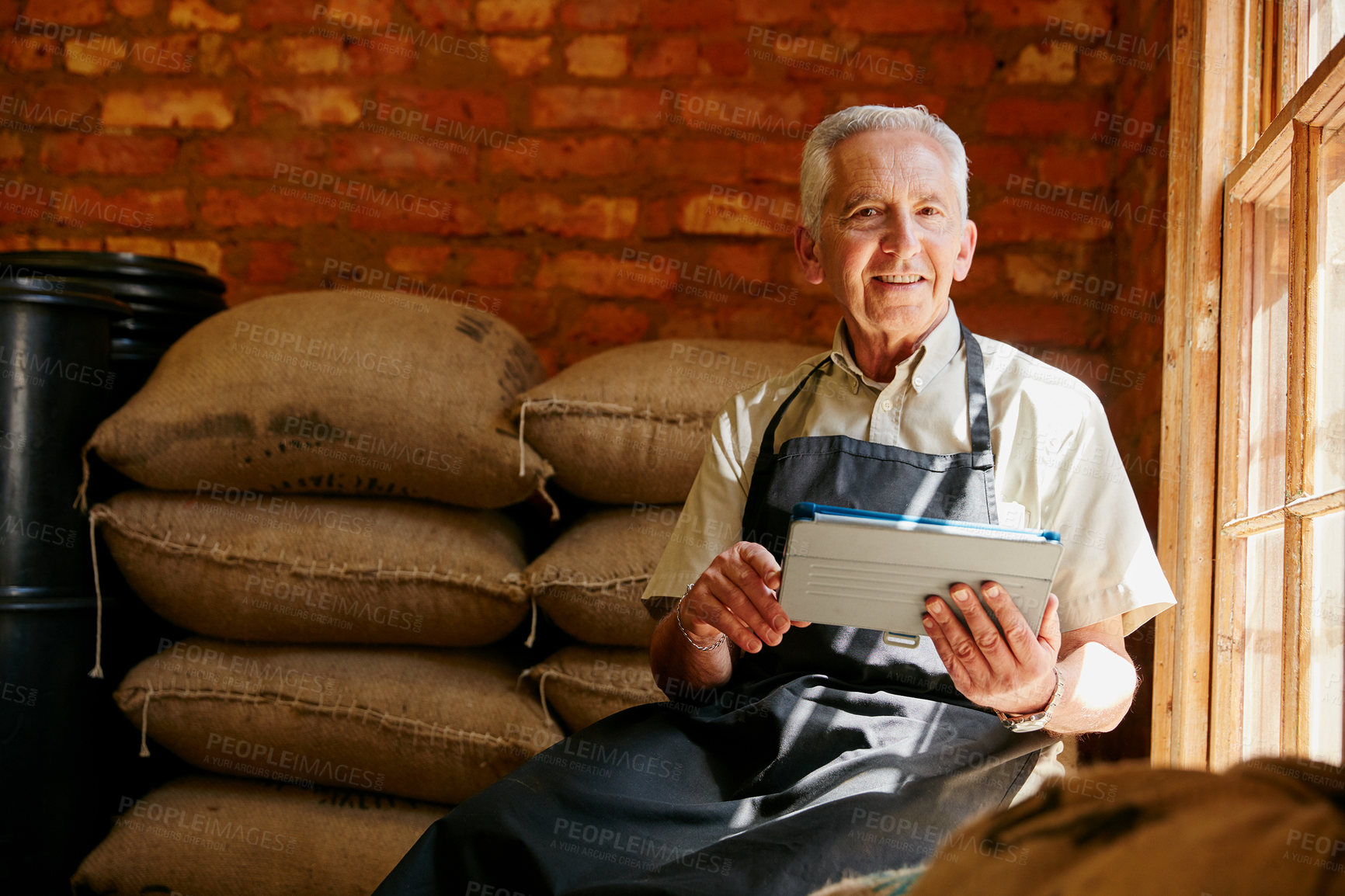Buy stock photo Cropped portrait of a senior man using a tablet while working in a roastery