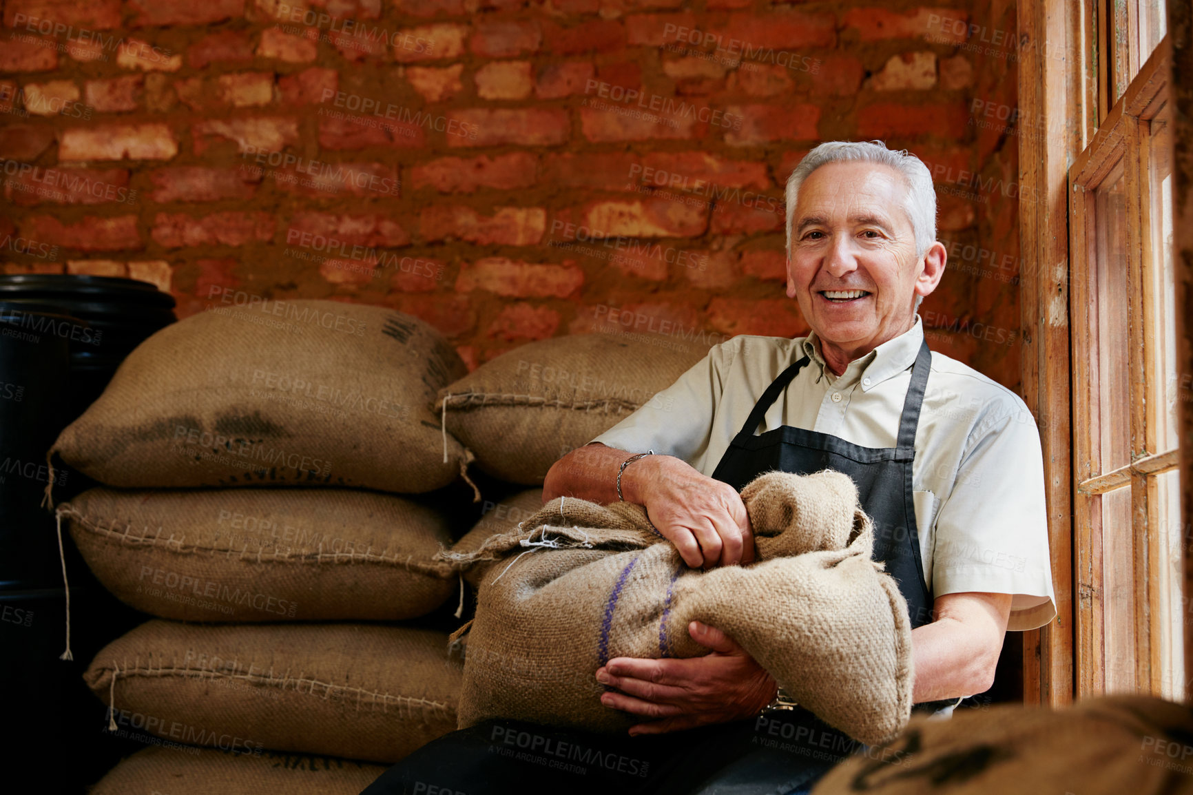 Buy stock photo Cropped portrait of a senior man holding a sack of coffee beans while sitting in a roastery