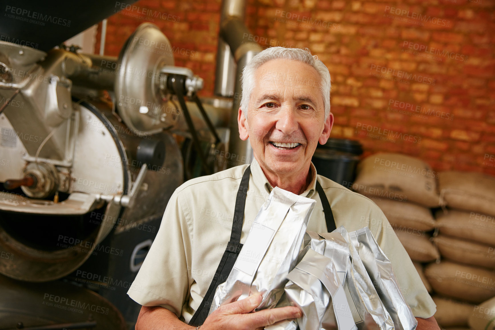 Buy stock photo Cropped portrait of a senior man holding bags of coffee beans while working in a roastery