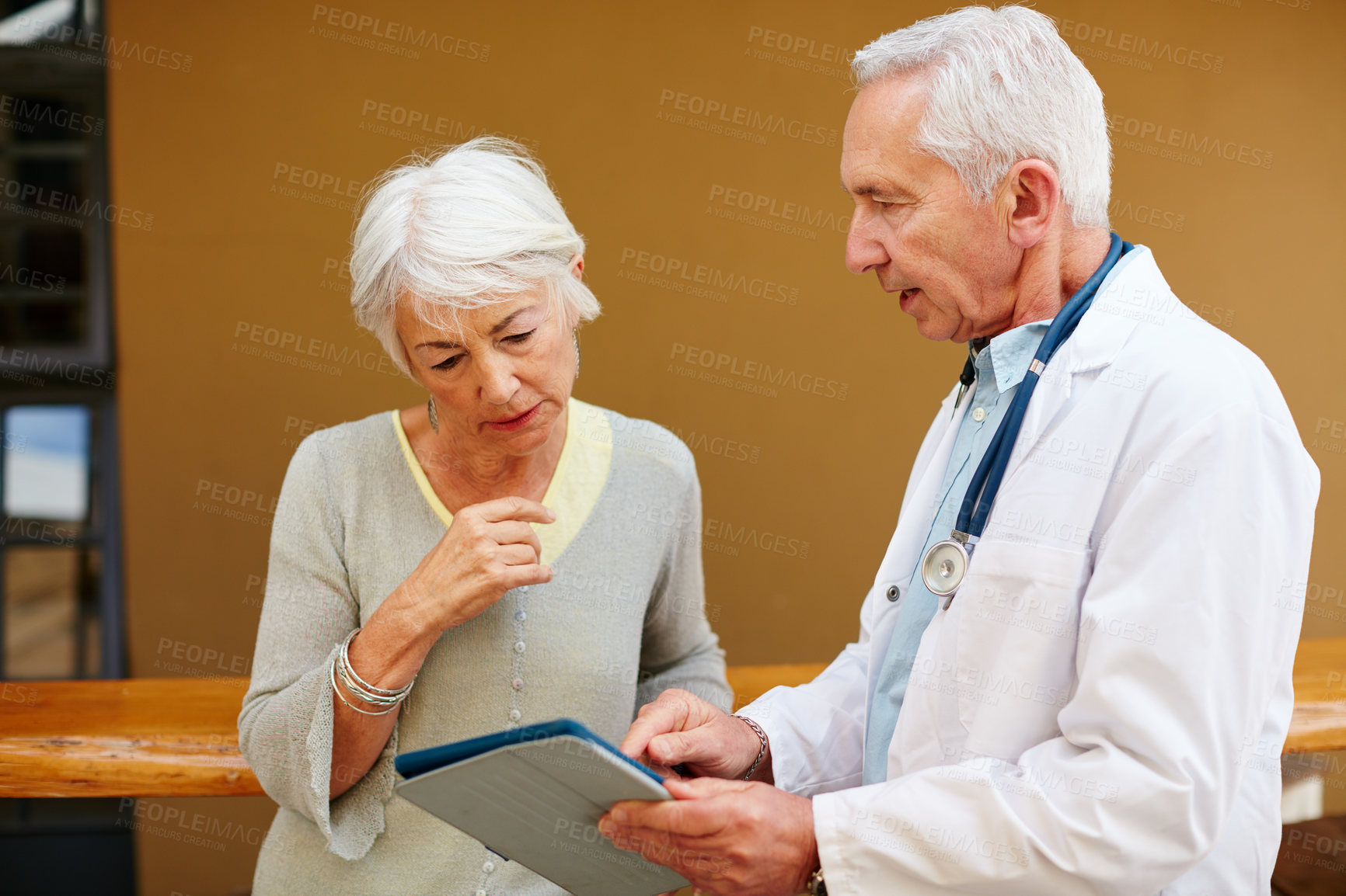 Buy stock photo Shot of a senior woman discussing test results with her doctor on a digital tablet