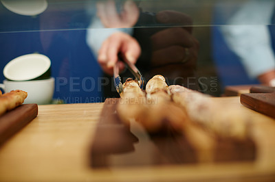 Buy stock photo Cropped shot of a deli worker choosing a bread stick from the display