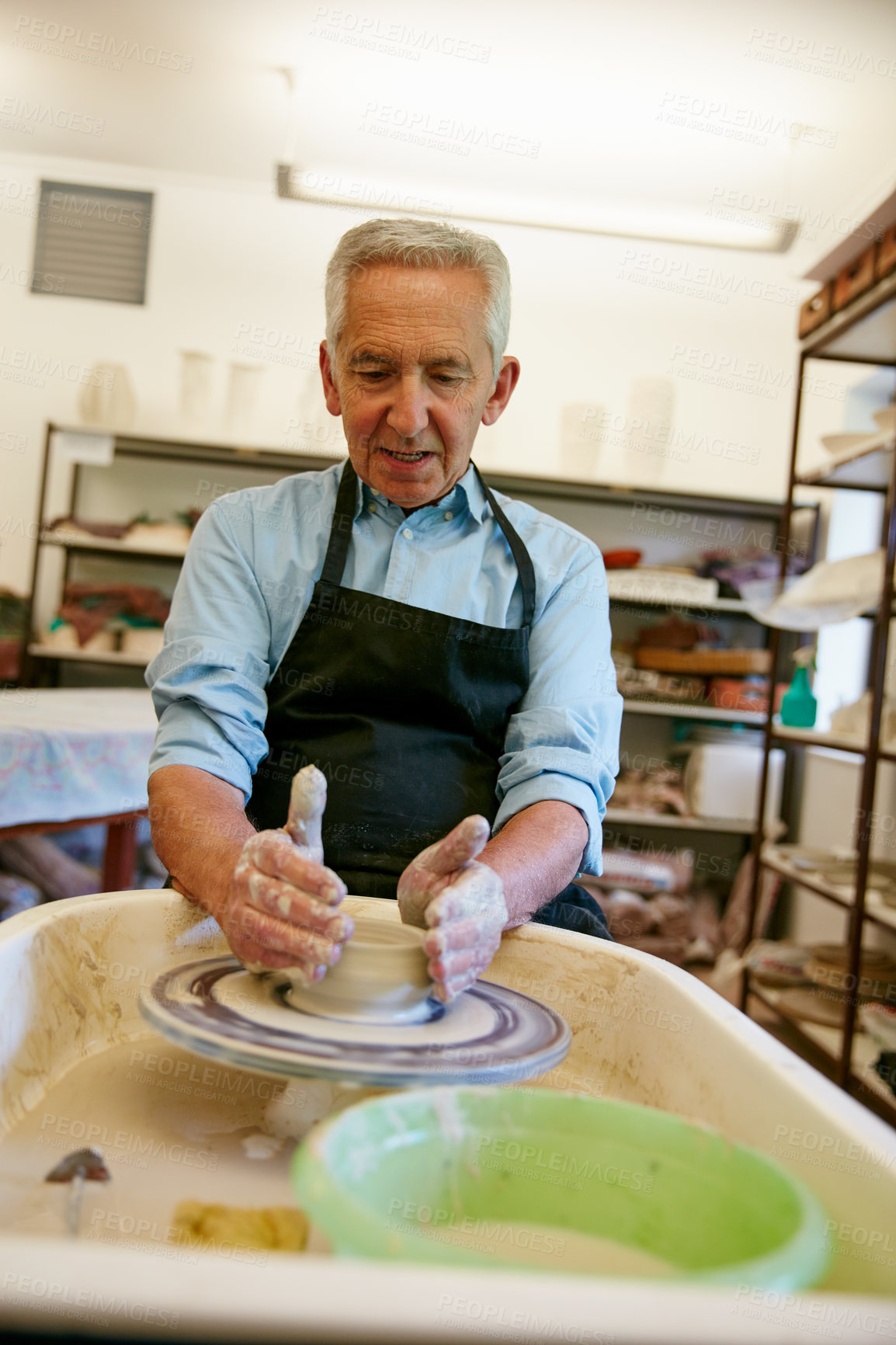 Buy stock photo Shot of a senior man making a ceramic pot in a workshop
