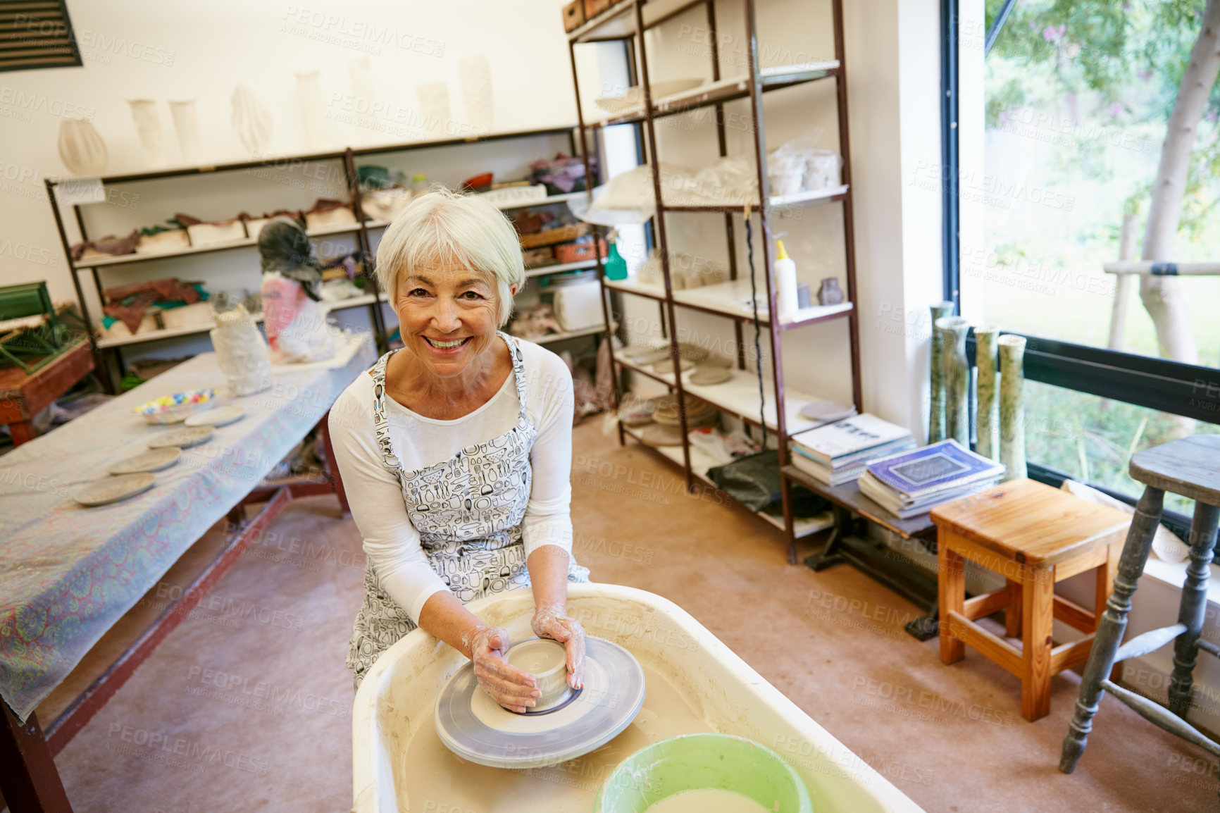 Buy stock photo Shot of a senior woman making a ceramic pot in a workshop