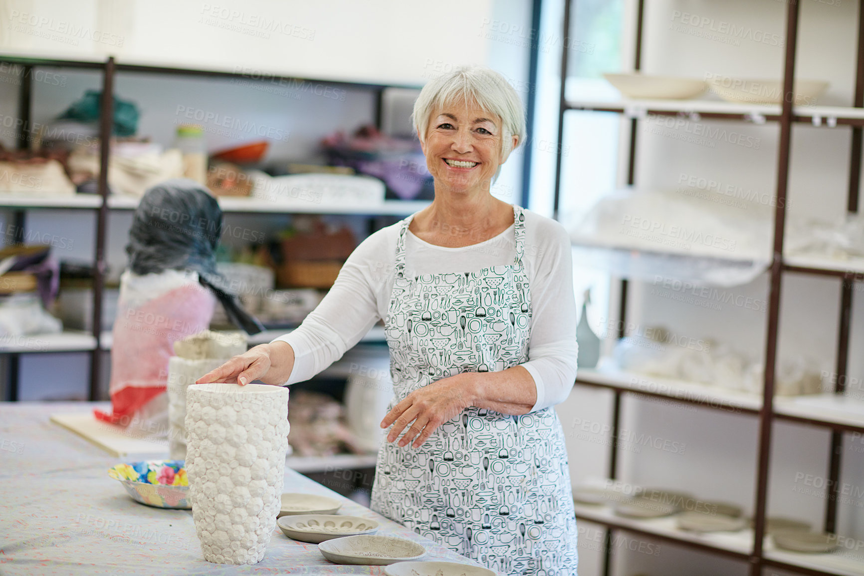 Buy stock photo Shot of a senior woman making a ceramic pot in a workshop