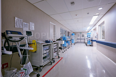Buy stock photo Shot of an empty passage way with medical equipment alongside the walls at a hospital