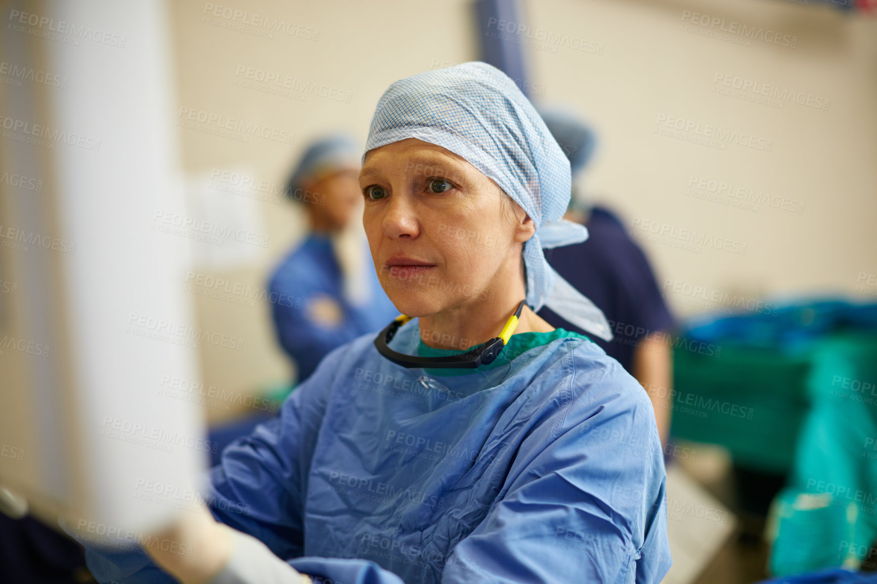 Buy stock photo Shot of a surgeon looking at a monitor in an operating room