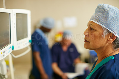 Buy stock photo Shot of a surgeon looking at a monitor in an operating room