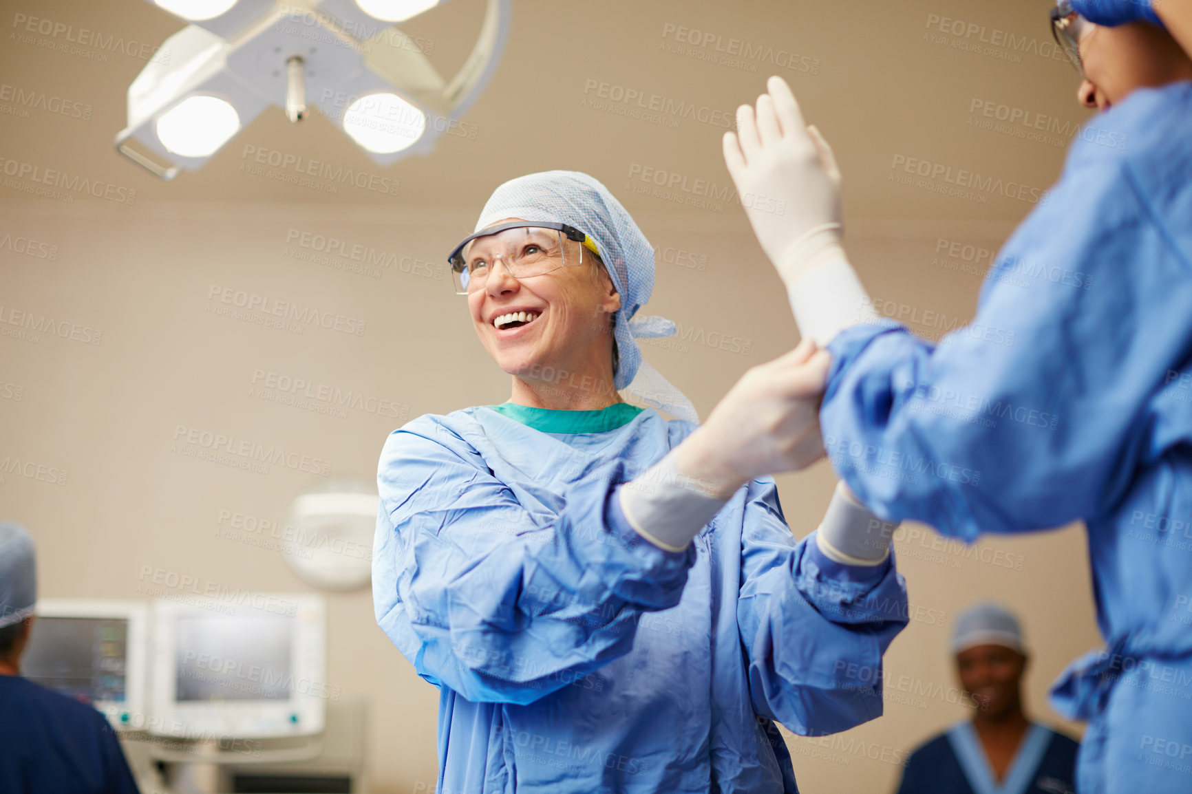 Buy stock photo Shot of surgeons putting on surgical gloves in preparation for a surgery