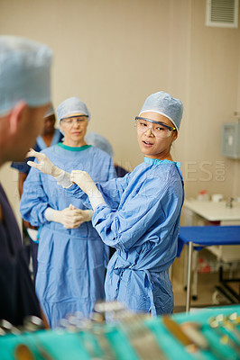 Buy stock photo Shot of surgeons putting on surgical gloves in preparation for a surgery