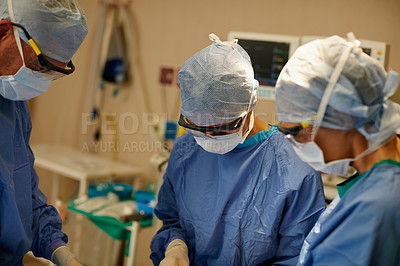 Buy stock photo Shot of a team of surgeons performing a surgical procedure in an operating room