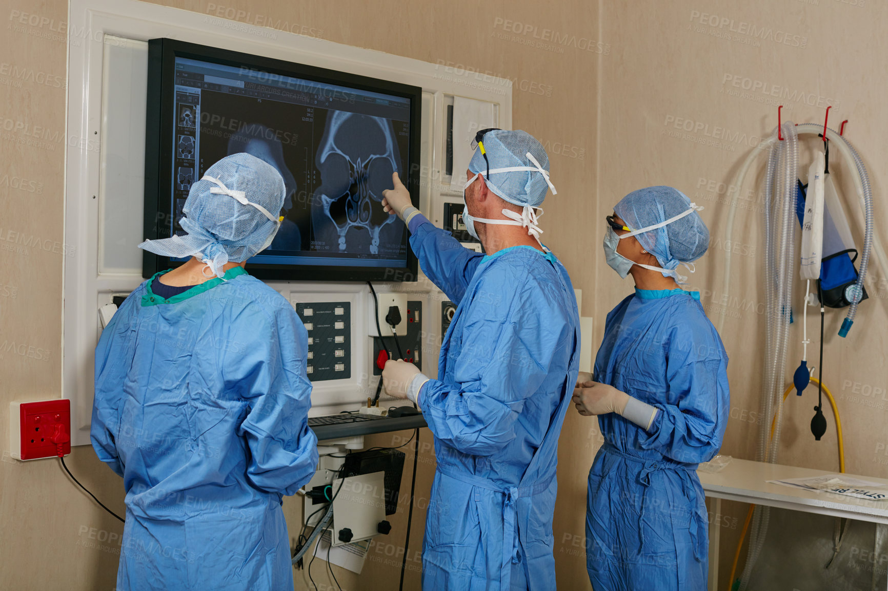 Buy stock photo Shot of a team of surgeons discussing a patient’s medical scans during surgery