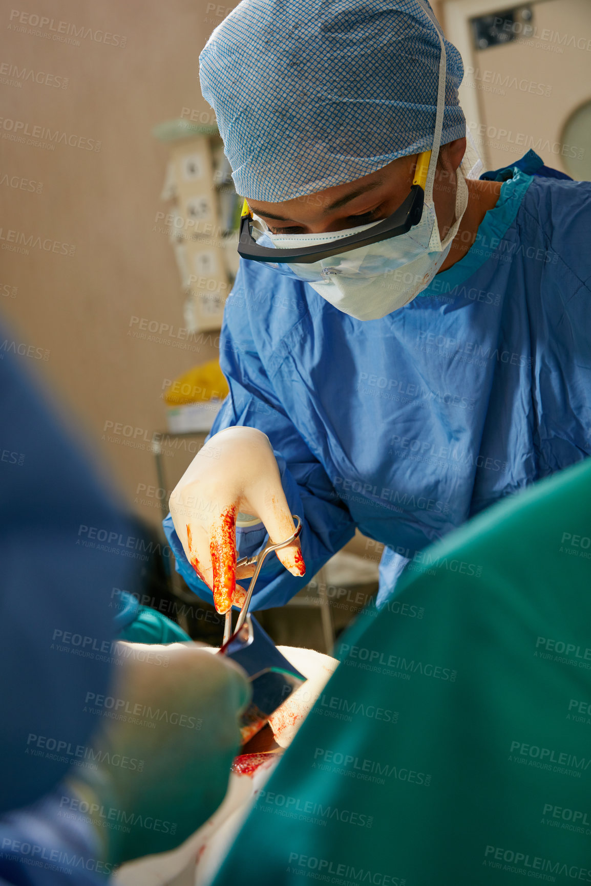 Buy stock photo Shot of a team of surgeons performing a surgery in an operating room