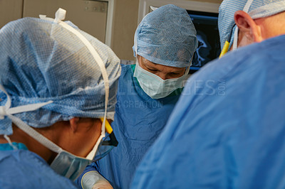 Buy stock photo Shot of a team of surgeons performing a surgery in an operating room