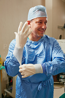 Buy stock photo Shot of a surgeon putting on surgical gloves in preparation for a surgery