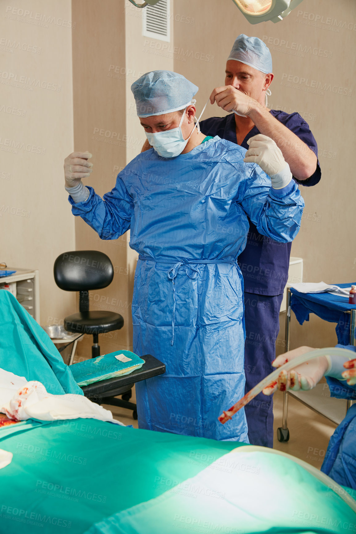 Buy stock photo Shot of two surgeons helping each other get dressed for surgery