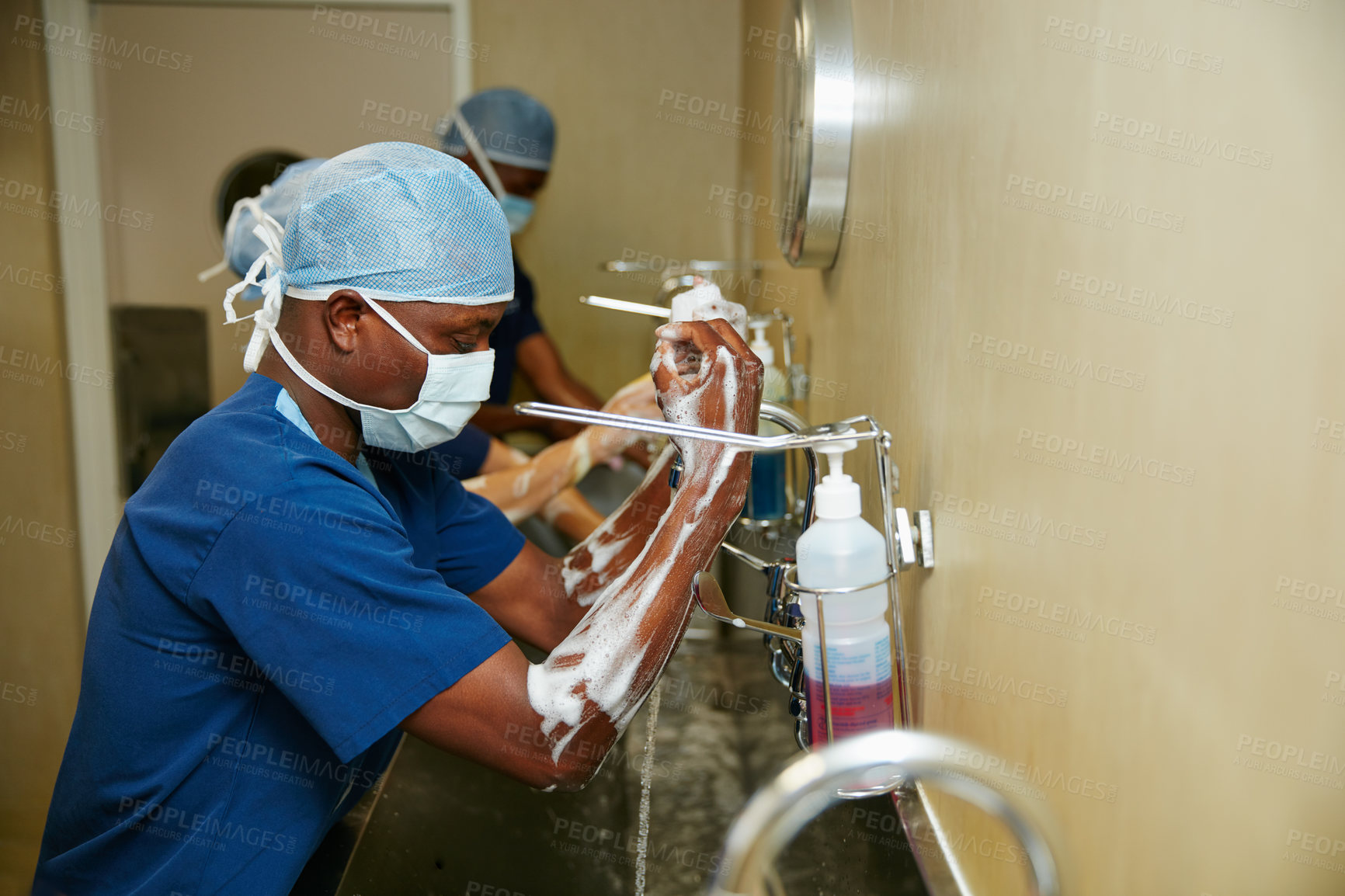 Buy stock photo Shot of a team of surgeons sterilizing their arms and hands as part of a surgical routine