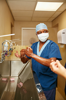 Buy stock photo Shot of a team of surgeons sterilizing their arms and hands as part of a surgical routine