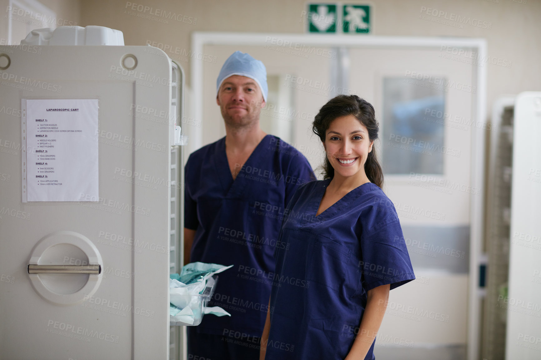 Buy stock photo Portrait, surgeon or woman with man in hospital, medical supply cart or operation preparation. Healthcare, pride or doctors smile with surgical equipment for laparoscopic procedure, hallway or team