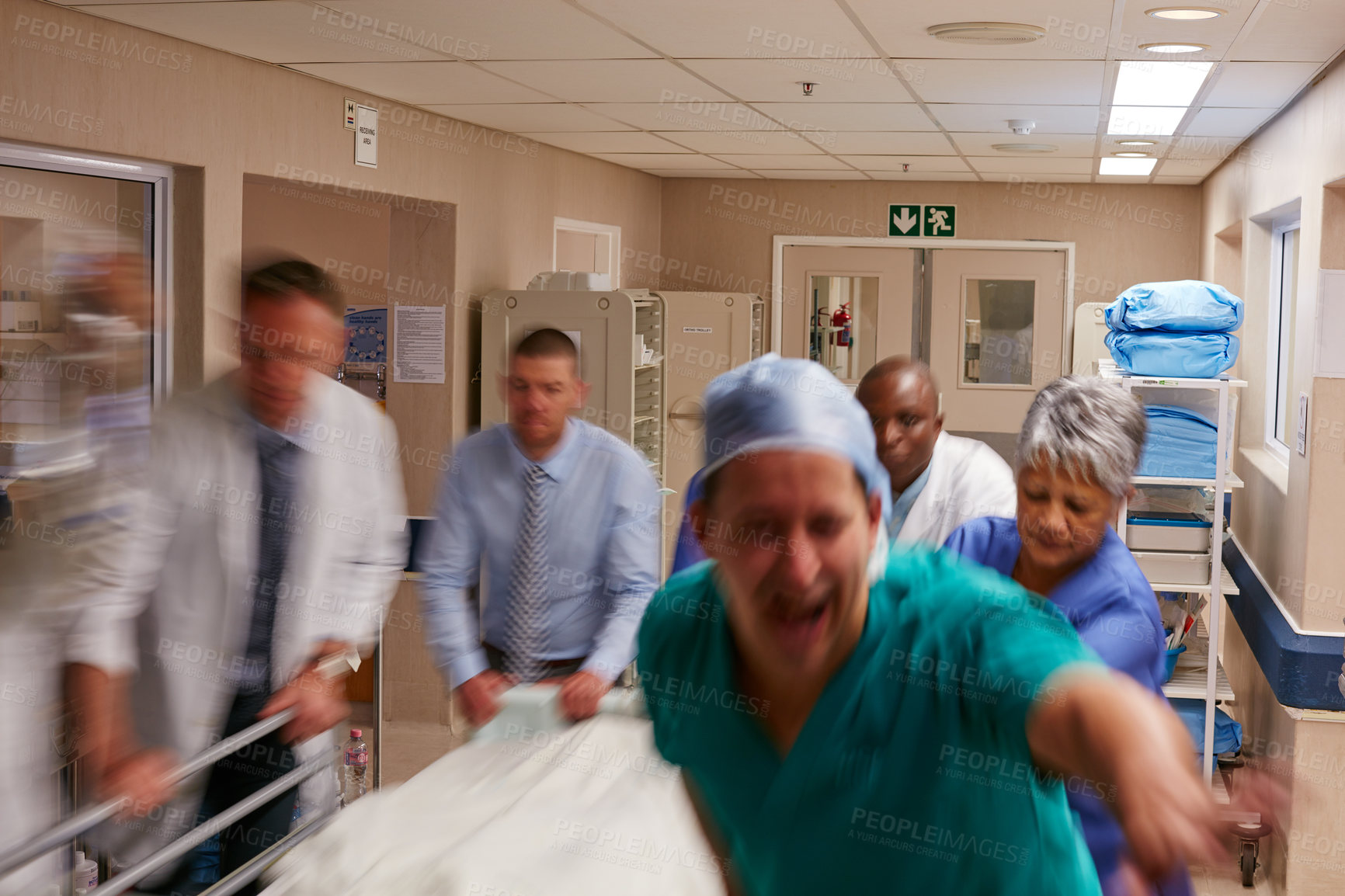 Buy stock photo Shot of a medical teamrushing a gurney through a hospital corridor