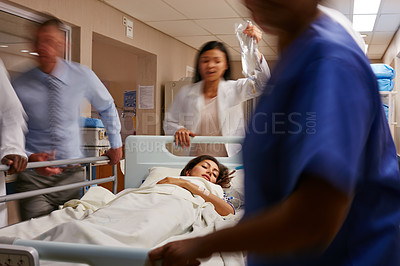 Buy stock photo Shot of a medical teamrushing a gurney through a hospital corridor