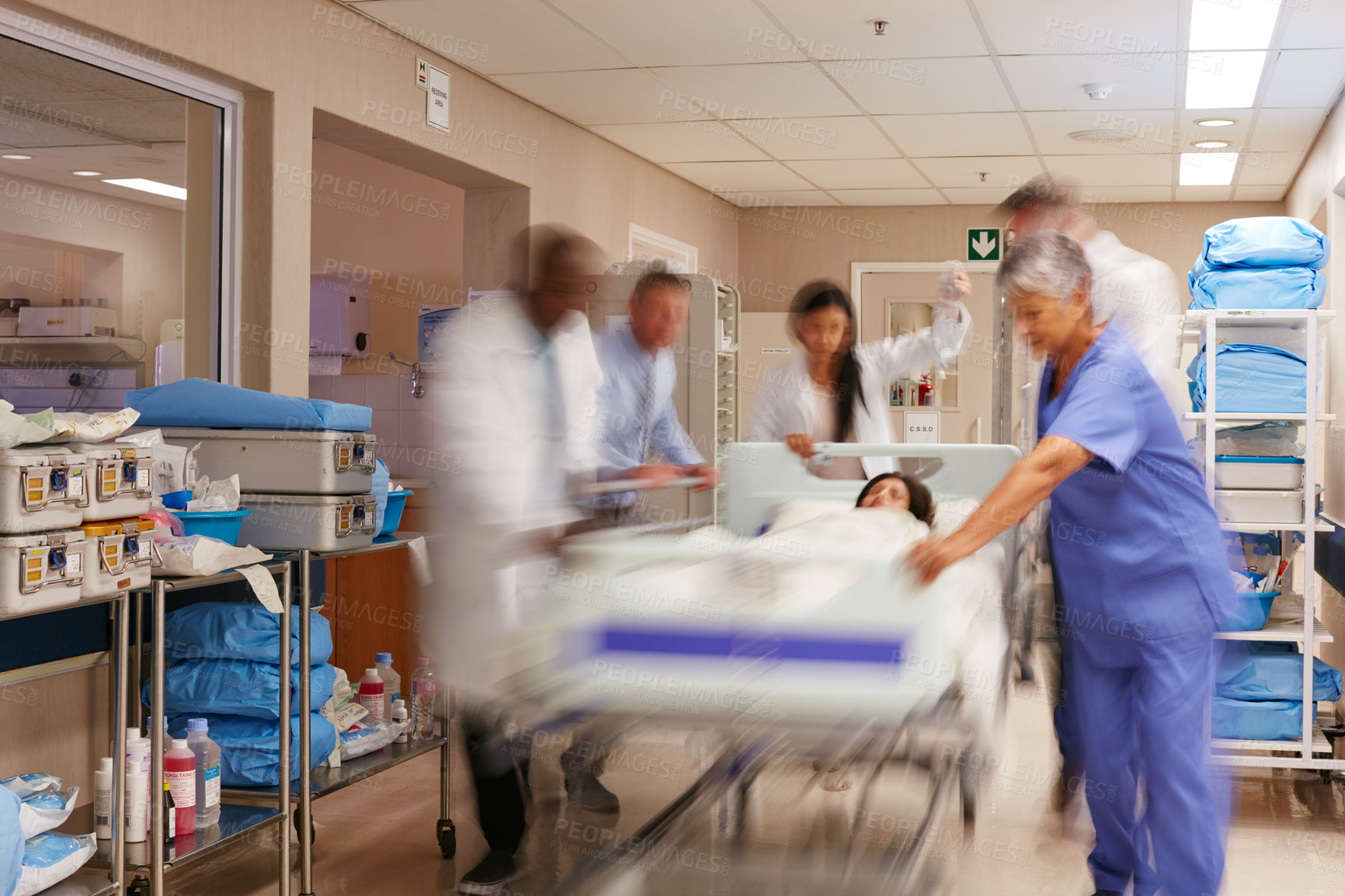 Buy stock photo Shot of a medical teamrushing a gurney through a hospital corridor