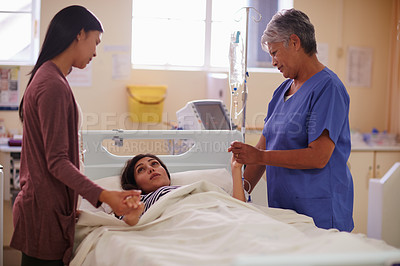 Buy stock photo Shot of a patient lying in bed while her visitor and nurse comforts her