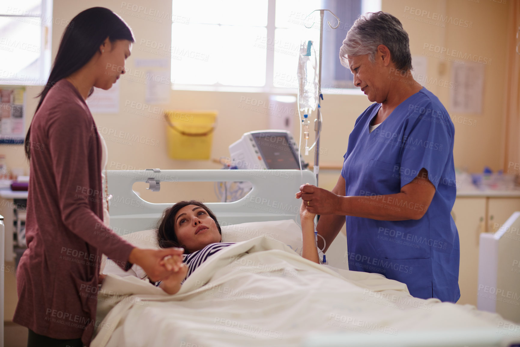 Buy stock photo Shot of a patient lying in bed while her visitor and nurse comforts her