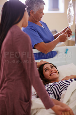 Buy stock photo Shot of a woman touching her friend's forehead as she lays in her hospital bed