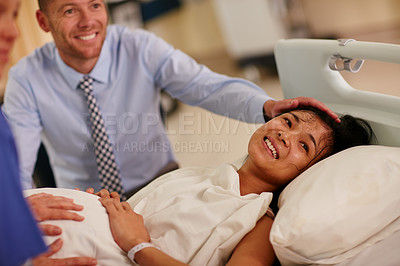 Buy stock photo Shot of a young woman lying in hospital with her husband in the background
