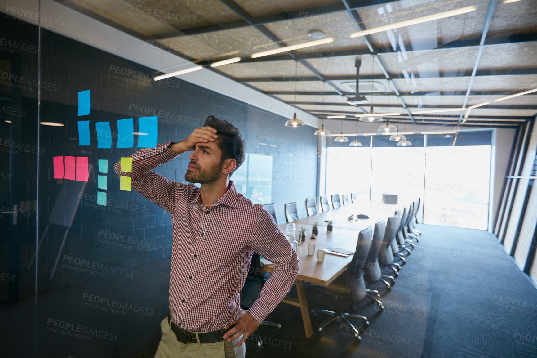 Buy stock photo Shot of a young businessman looking at sticky notes on a glass wall