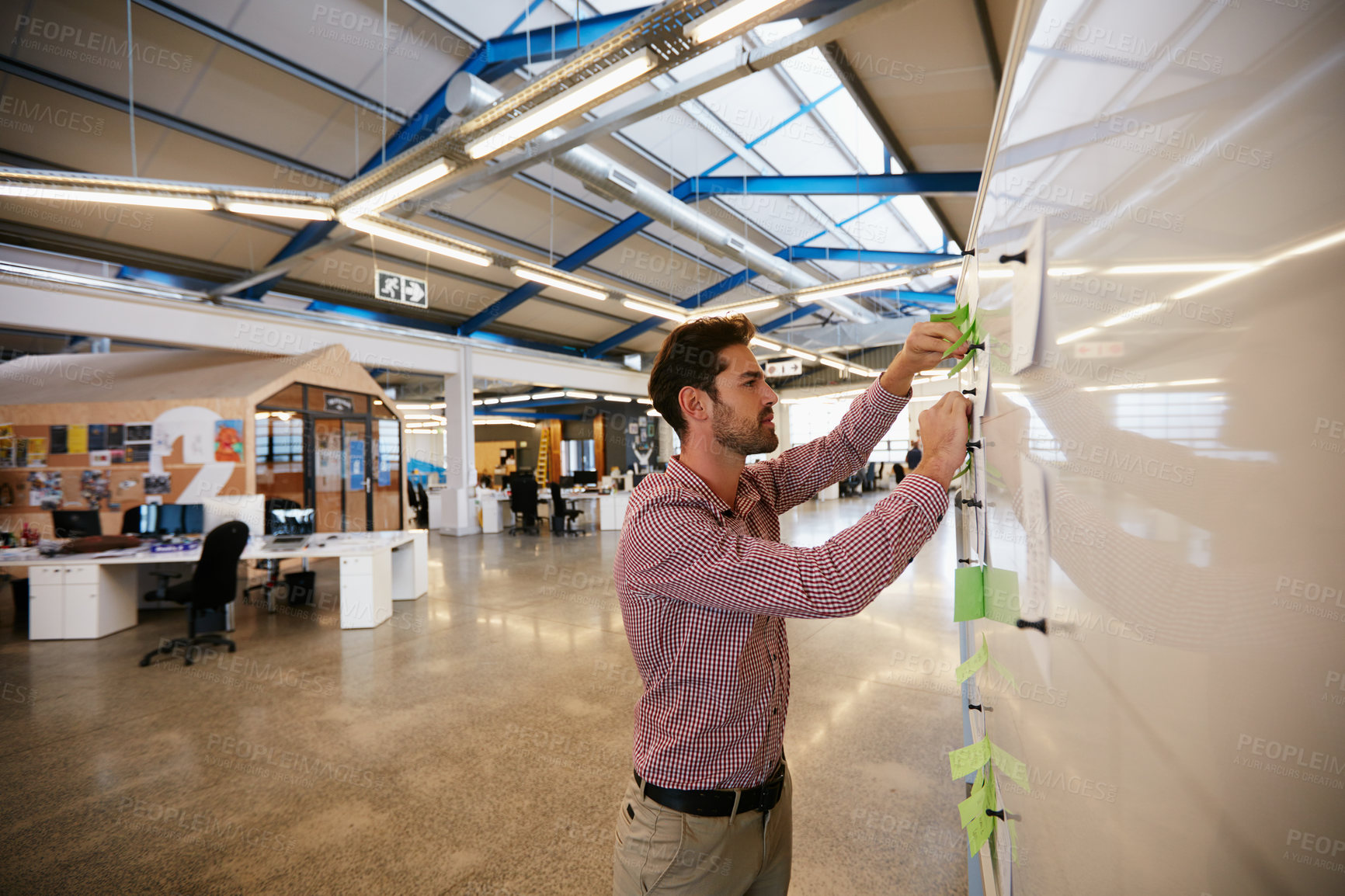 Buy stock photo Shot of a young businessman working on sticky notes on a whiteboard