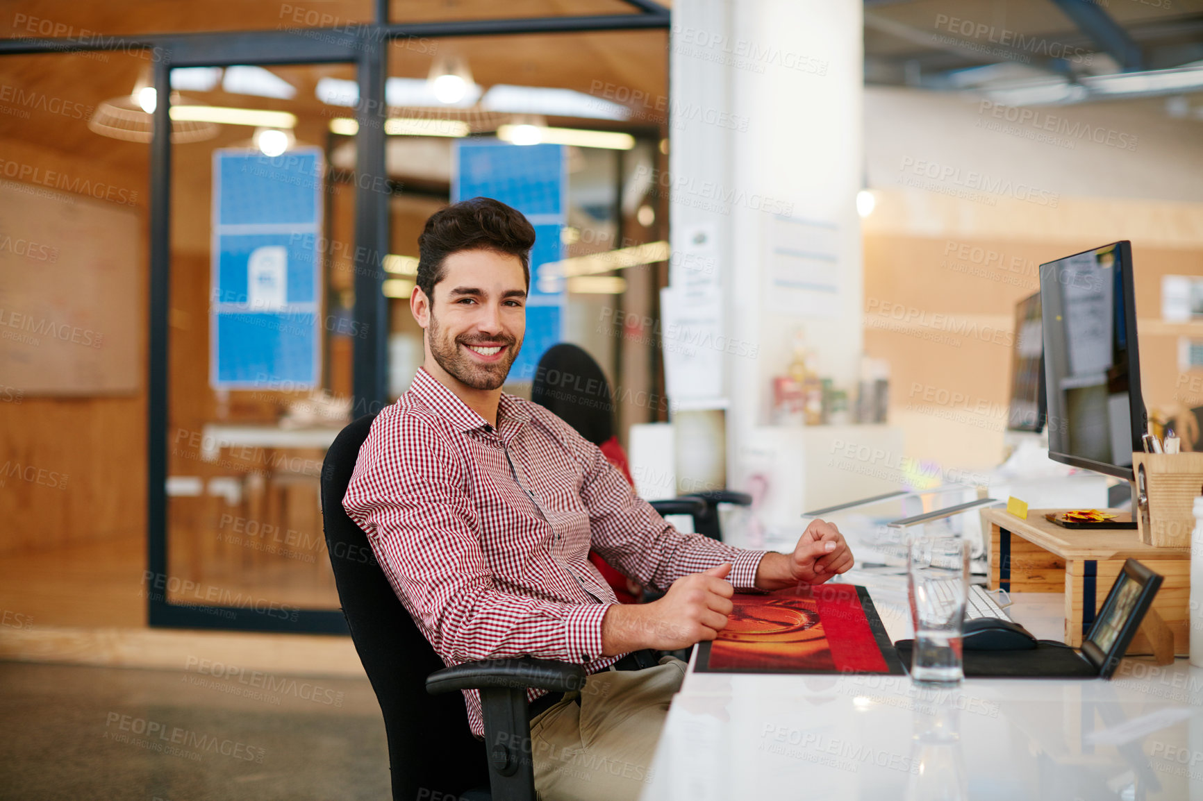 Buy stock photo Shot of a young businessman sitting at his desk