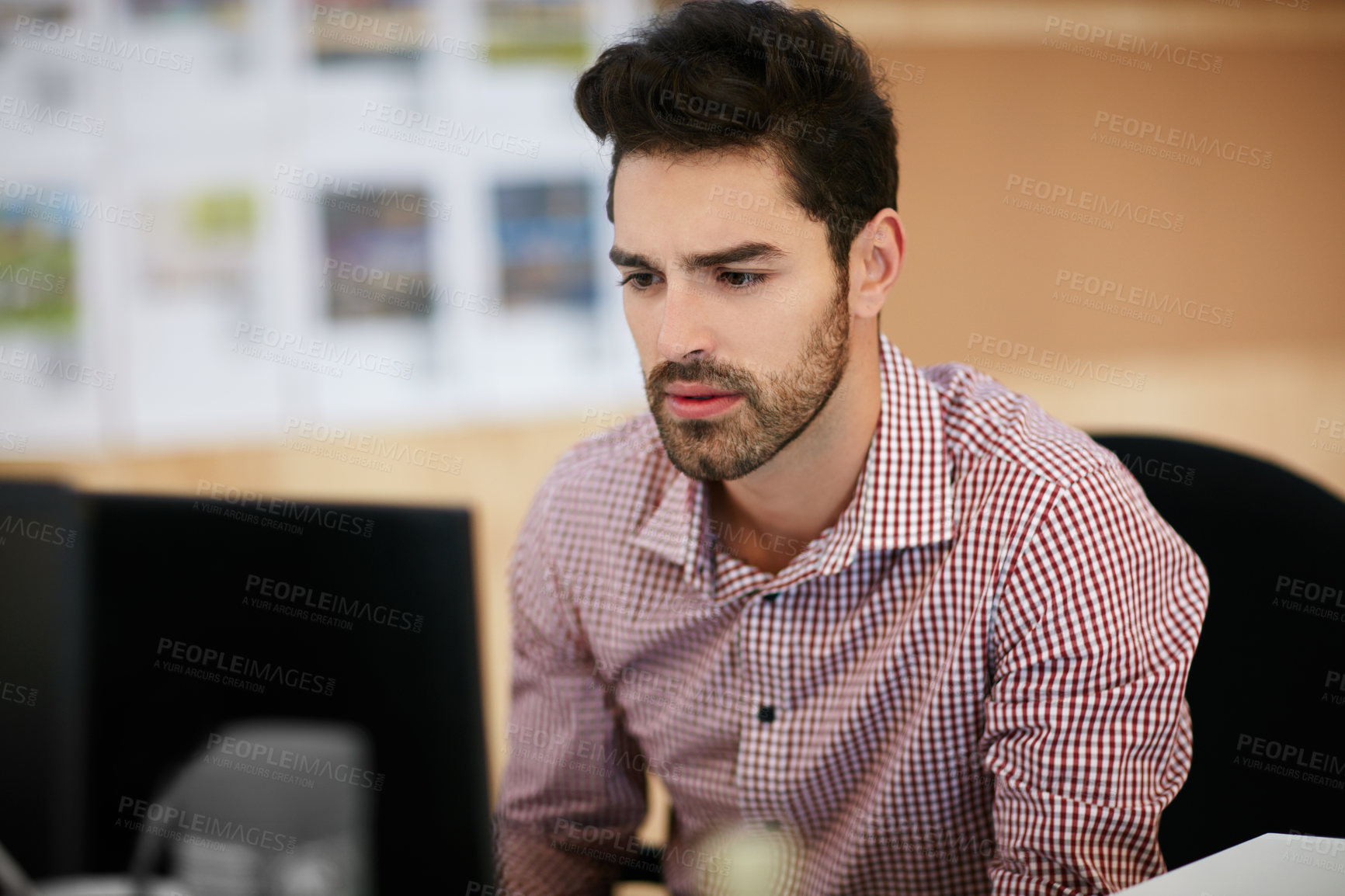 Buy stock photo Shot of a young businessman sitting at his desk