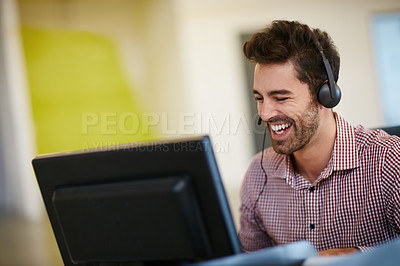 Buy stock photo Shot of a friendly young call centre agent sitting at his desk