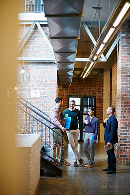 Buy stock photo Shot of a group of businesspeople having a discussion in the hallway