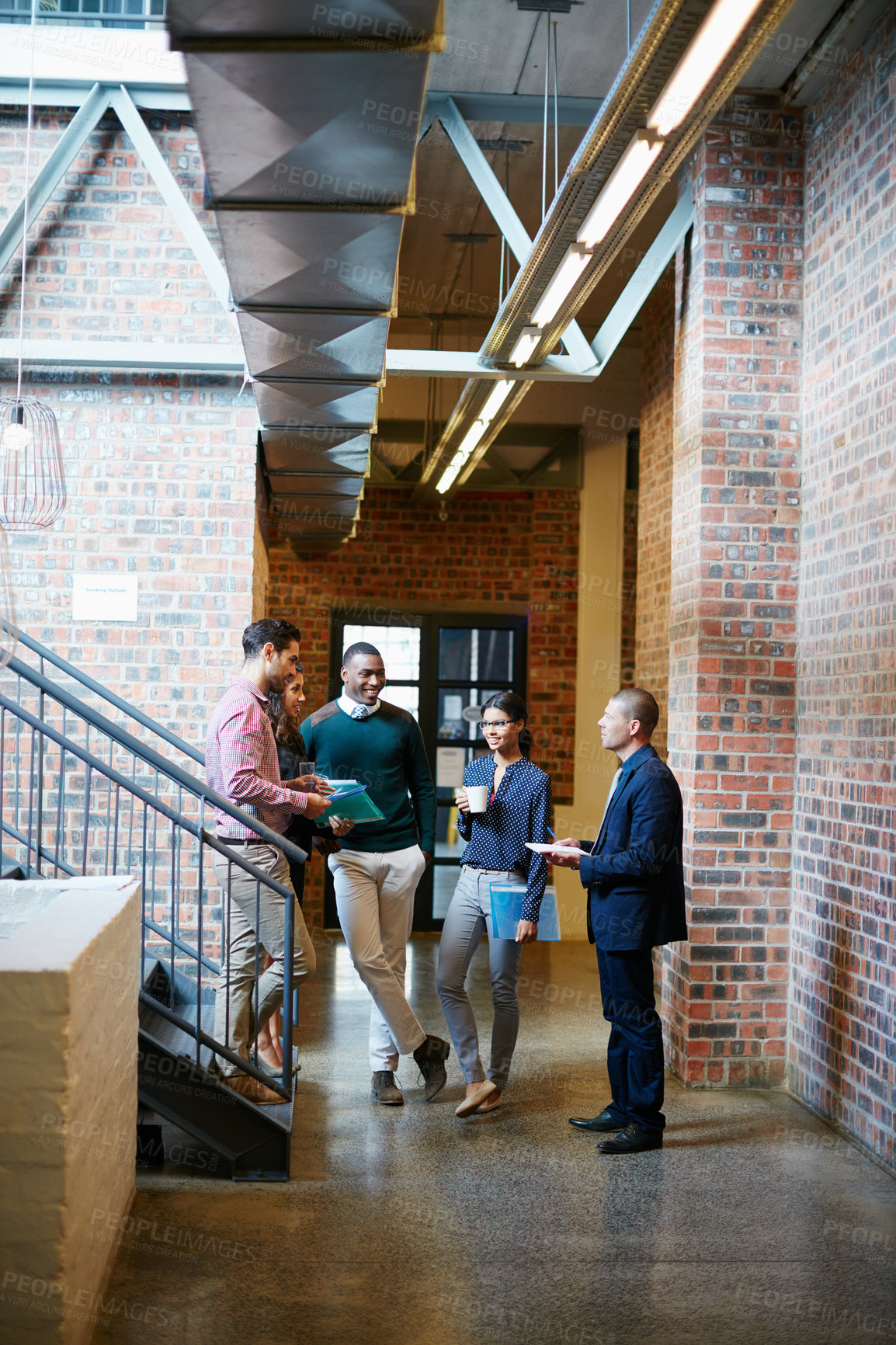 Buy stock photo Shot of a group of businesspeople having a discussion in the hallway