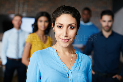 Buy stock photo Cropped portrait of a businesswoman standing in the workplace with her colleagues in the background