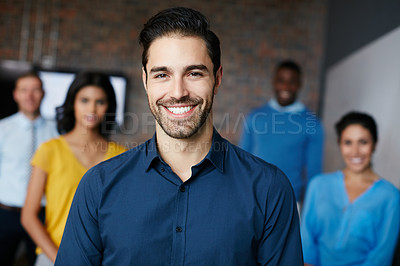 Buy stock photo Cropped portrait of a businessman standing in the workplace with his colleagues in the background