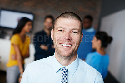 Buy stock photo Cropped portrait of a businessman standing in the workplace with his colleagues in the background