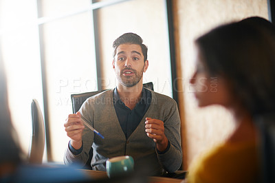 Buy stock photo Shot of a young man having a discussion with his colleagues in a meeting