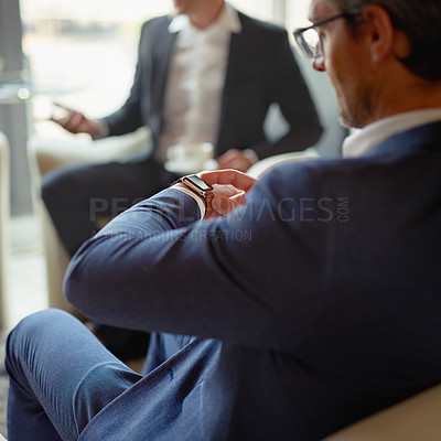 Buy stock photo Shot of a businessman checking his watch while sitting in a corporate office