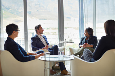Buy stock photo Shot of four businesspeople talking in a corporate office