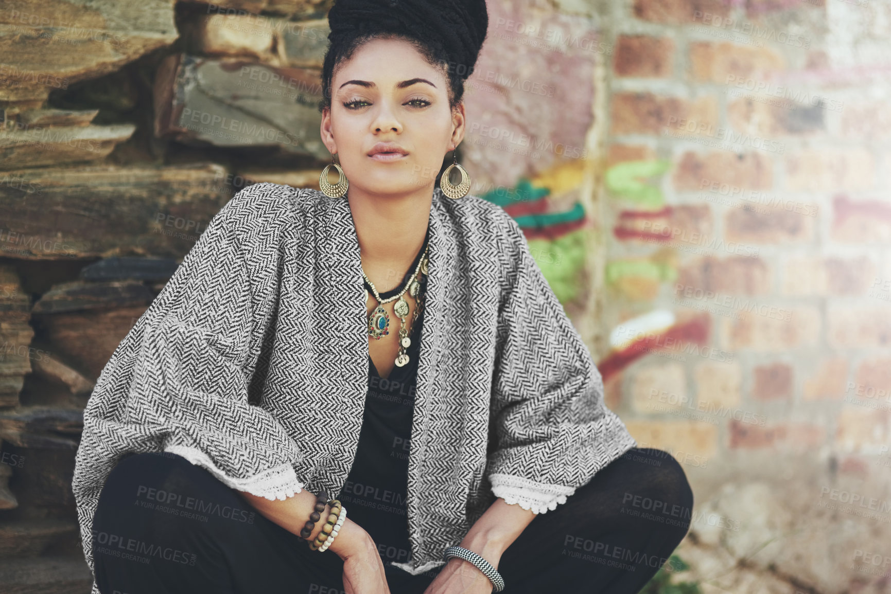 Buy stock photo Cropped shot of a fashionable young woman crouching against a wall