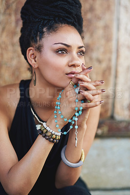 Buy stock photo Shot of an attractive young woman praying with her rosary outdoors